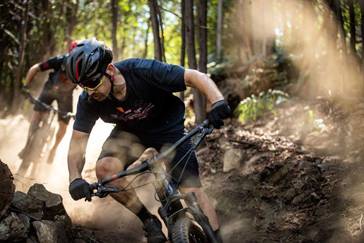 a guy leaning sideways around a corner while riding a mountain bike