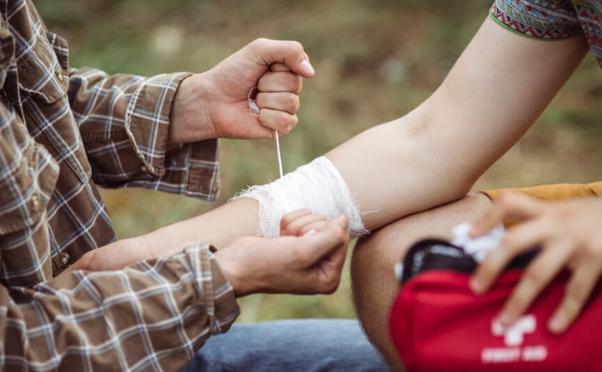 A Person Wrapping Their Friends Injured Arm In Gauze